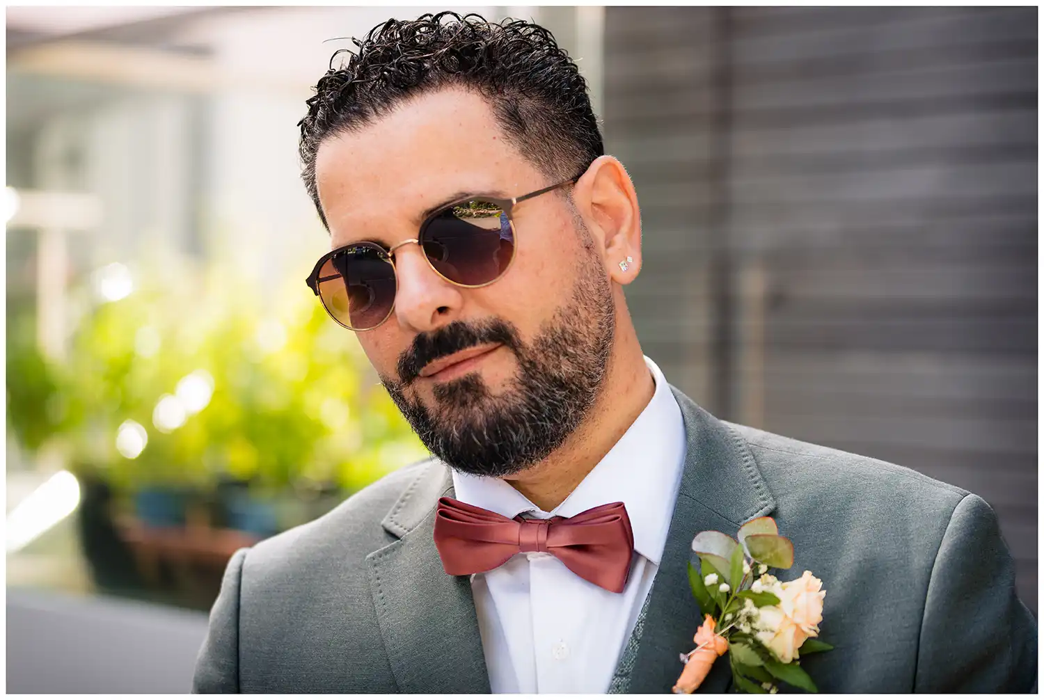 Stilvoller Bräutigam mit Brille, bunter Fliege und Blumenanstecker im Sakko bei einem modernen Hochzeitsfoto